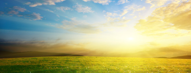 Sunrise over green field and rolling hills